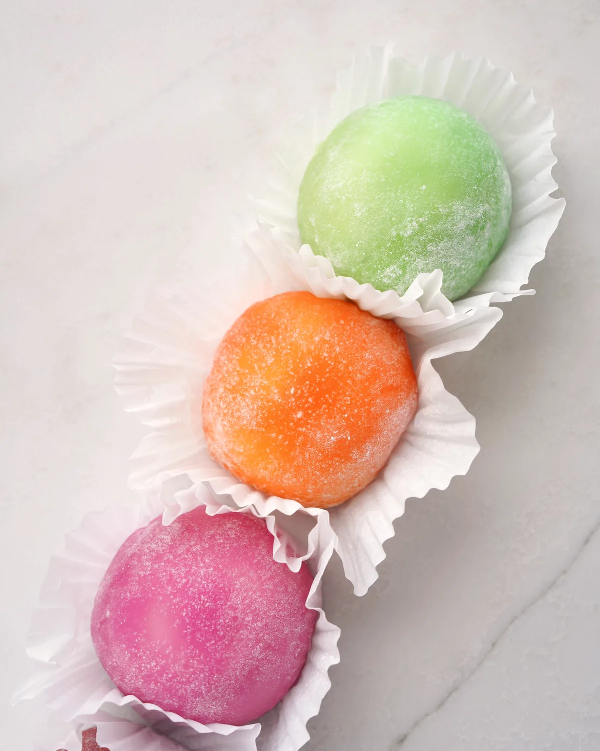 紙の敷き皿に並べた、抹茶と桃と紅の三色の菓子