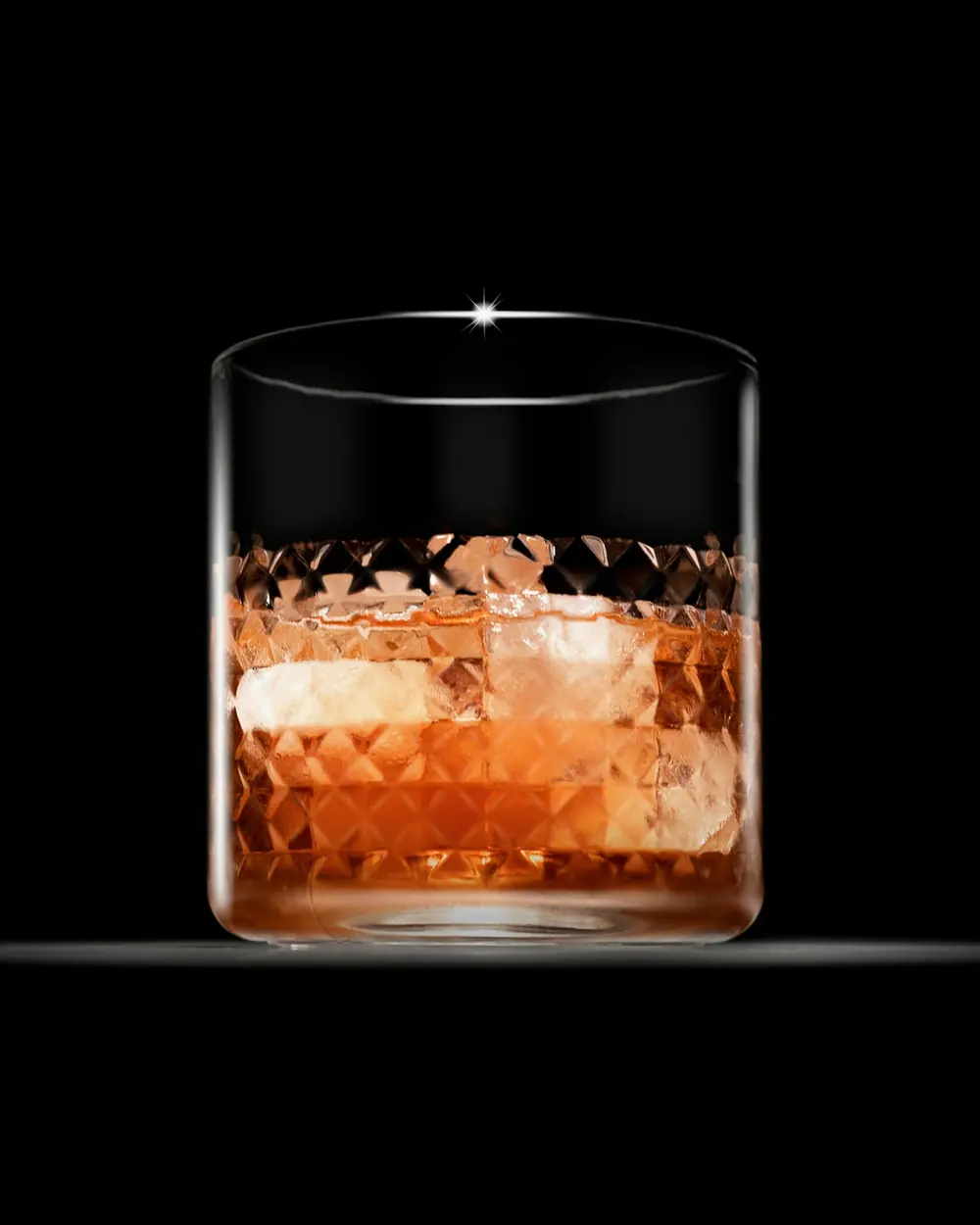 真っ暗な中に置かれた、丸い氷と琥珀の一杯