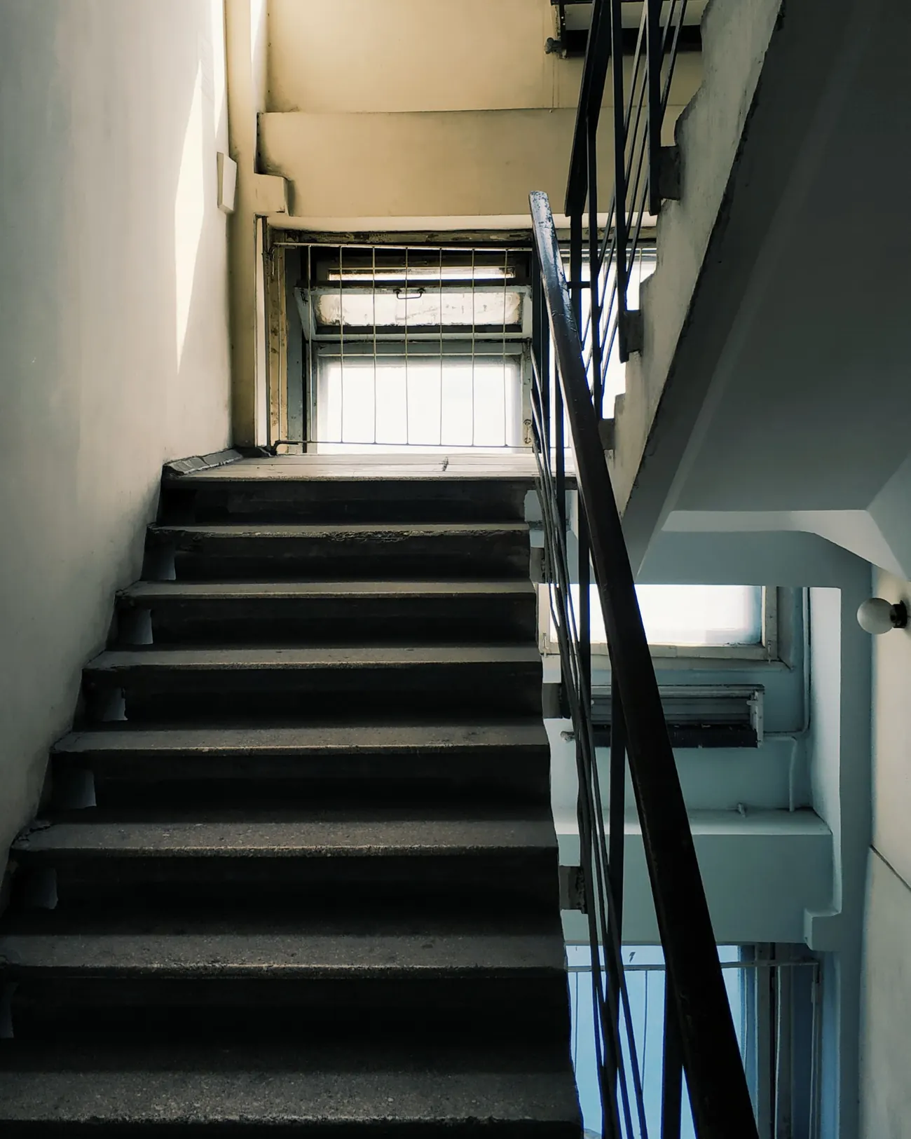 古い建物の細い階段。のぼりきった先の窓から光が差している